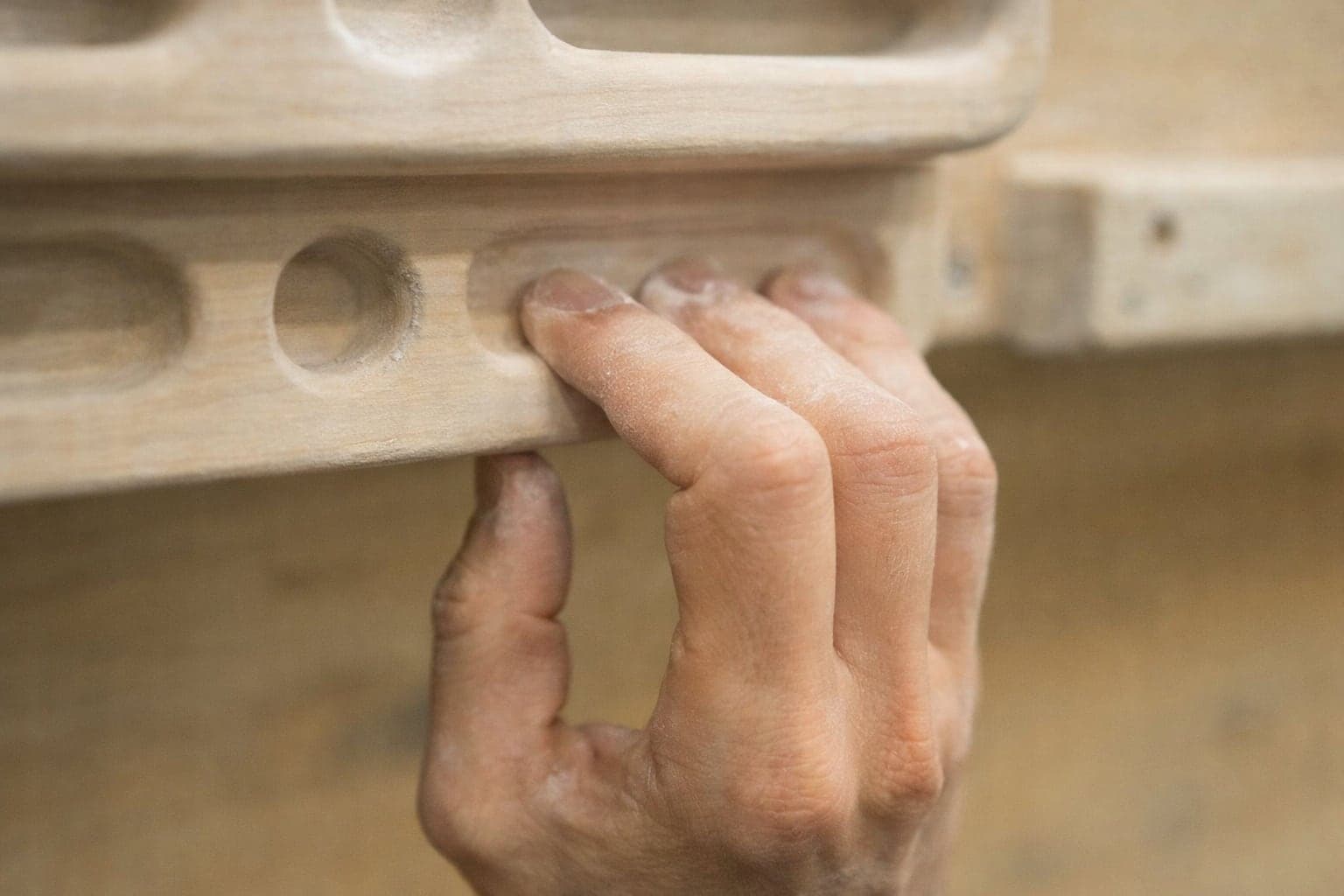 Close-up of a climber's hand on a hangboard during a finger strength training session.